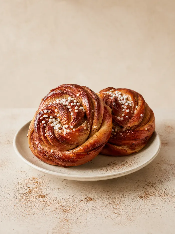 To kanelsnurrer med perlesukker på en tallerken