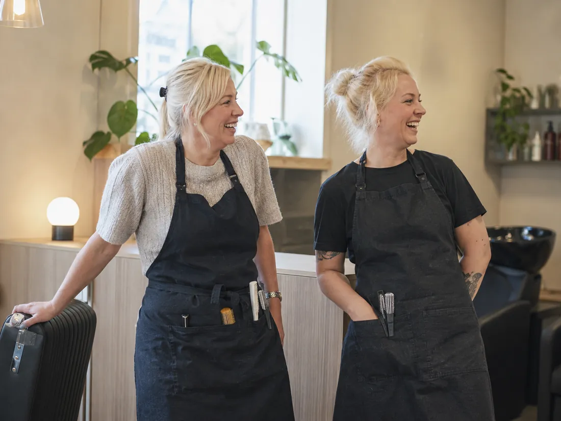 To frisører står og prater i salongen