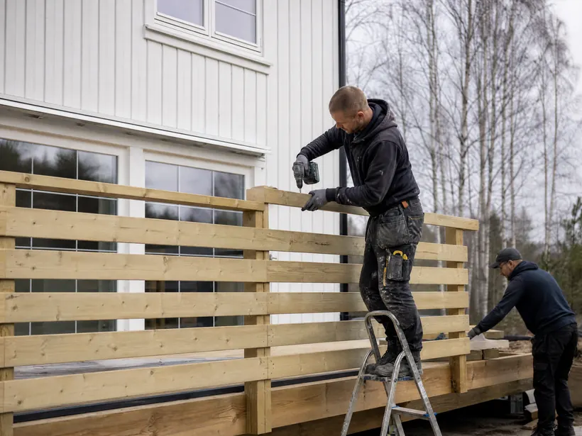 Håndverkere som setter opp rekkverk på en ny terrasse i lys furu