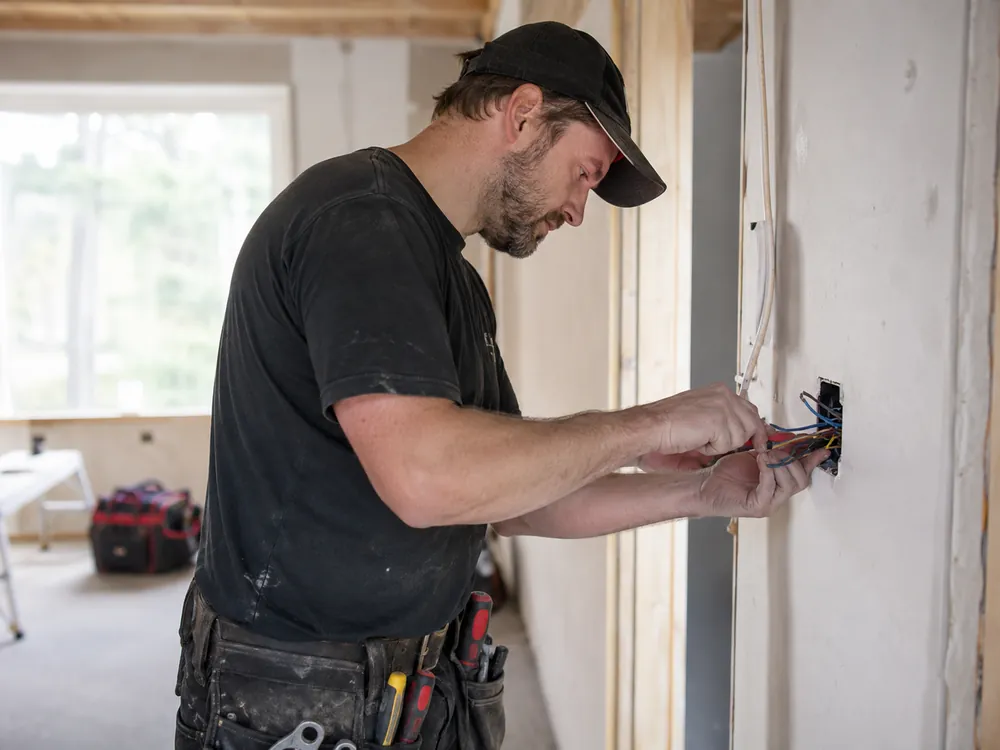 Elektriker som kobler en veggboks under arbeid