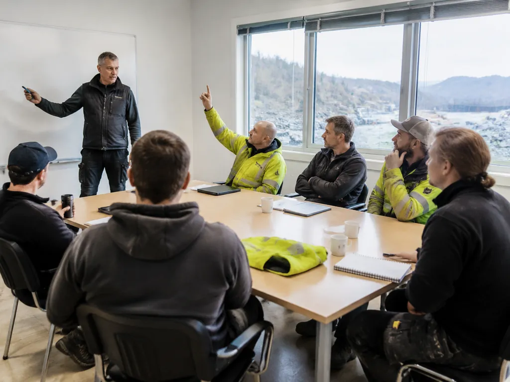 Instruktør leder et HMS-kurs for en liten gruppe rundt et møtebord