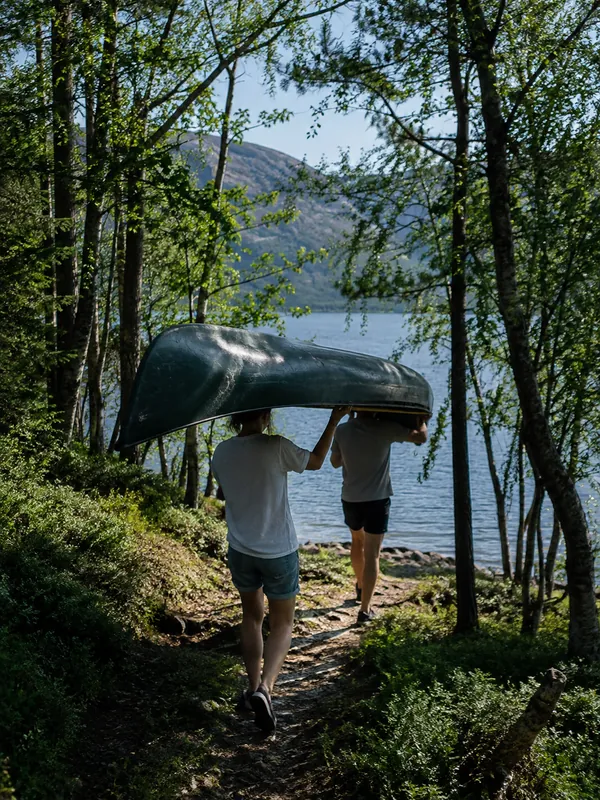 To personer bærer kano ned mot vannet